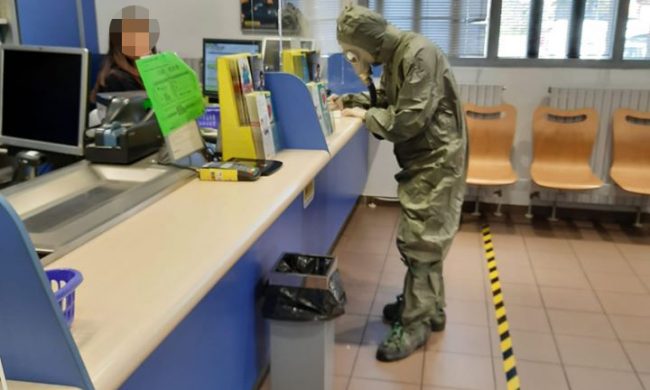 Con la tuta integrale e la maschera antigas alle poste